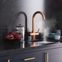 a swan neck copper hot water tap in a black kitchen