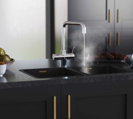 a D-shape chrome boiling water tap steaming hot water over a black sink