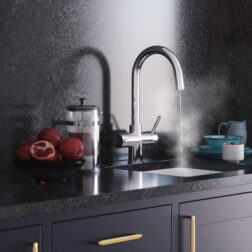 a chrome swan neck instant boiling tap dispensing hot water into a modern kitchen sink