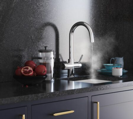 a chrome swan neck instant boiling tap dispensing hot water into a modern kitchen sink