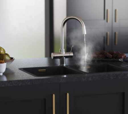 a swan neck chrome boiling water tap streaming hot water into a modern black kitchen sink