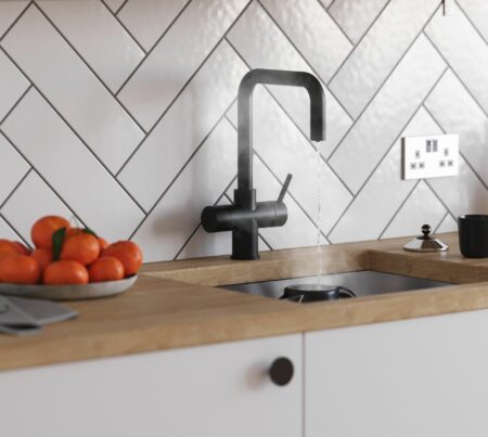 a D-shape matt black instant boiling tap with streaming hot water into a kettle