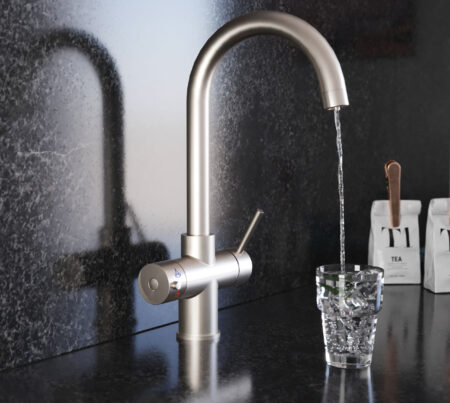 A swan neck hot water tap in brushed nickel pours water into a crystal glass