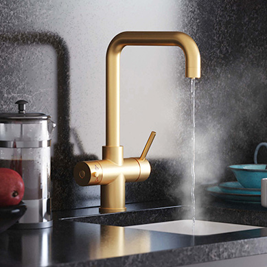 a black kitchen counter with a D-shape gold hot water tap with boiling water running from spout into a sink