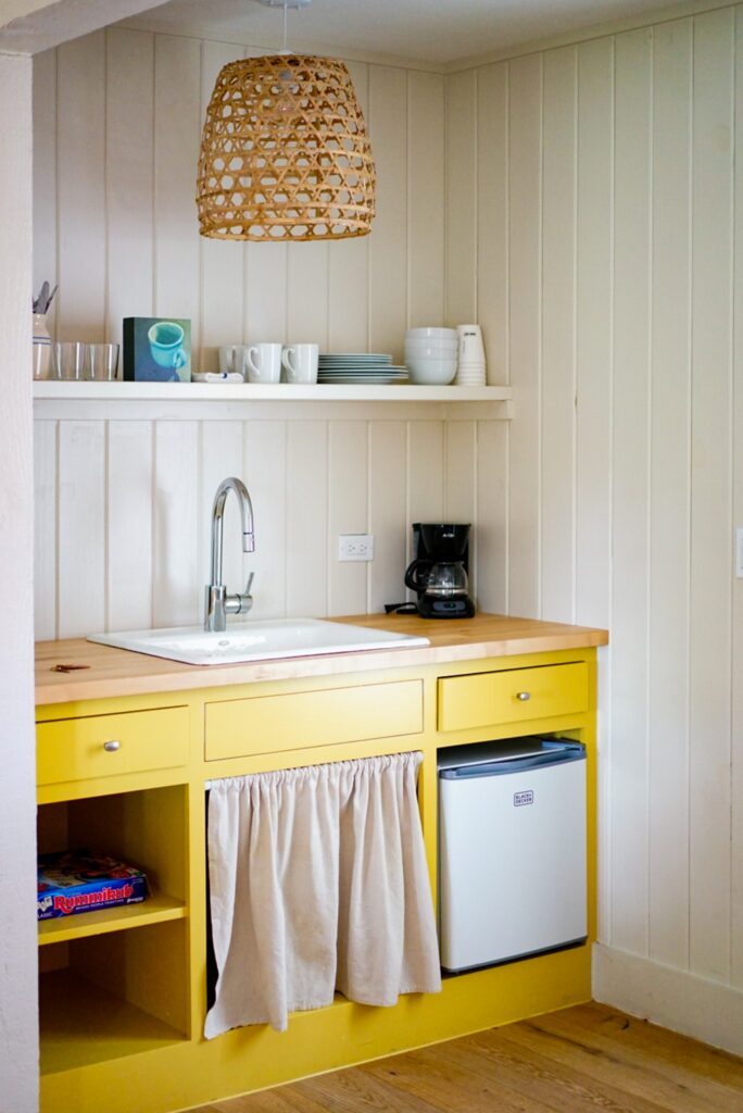 kitchen with yellow cupboards, shelves and a rattan lampshade