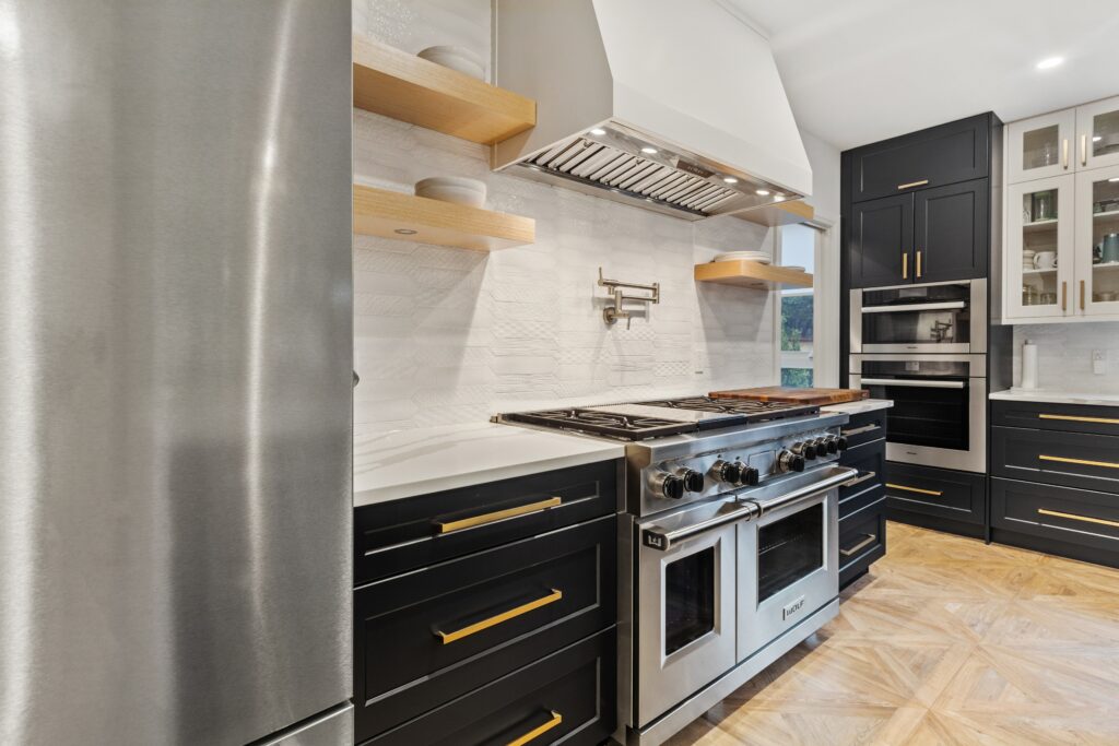 interior view of a kitchen having black cabinets with gold handles beside a white oven