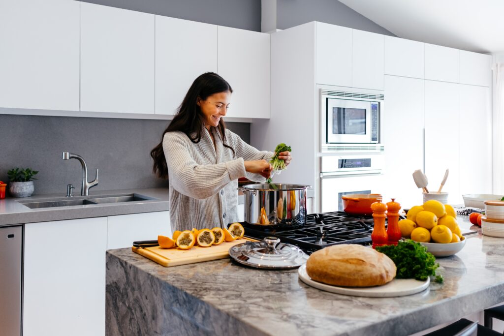 a woman cooking in a kitchen island's range cooker with a chrome water tap at her back