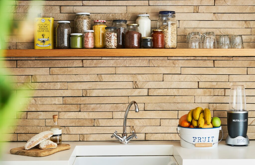 kitchen with real brick backsplash, chrome swan neck tap, and a long wooden shelf with condiments