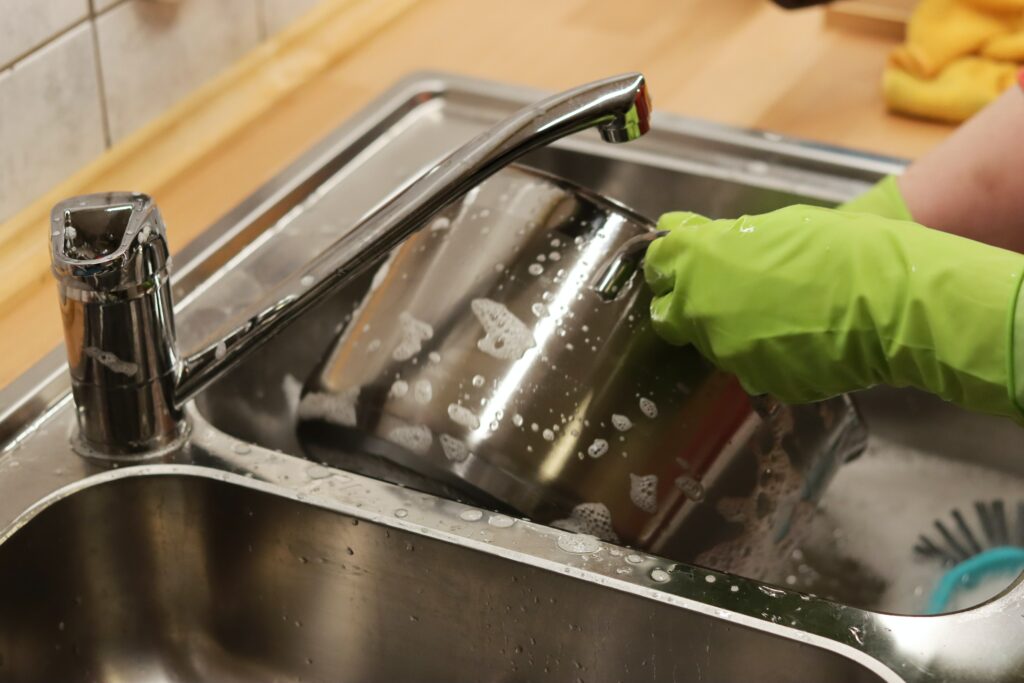 a person cleaning a pan in the kitchen sink