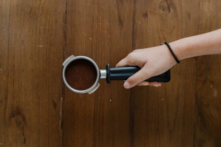 Crop barista hand with ground coffee