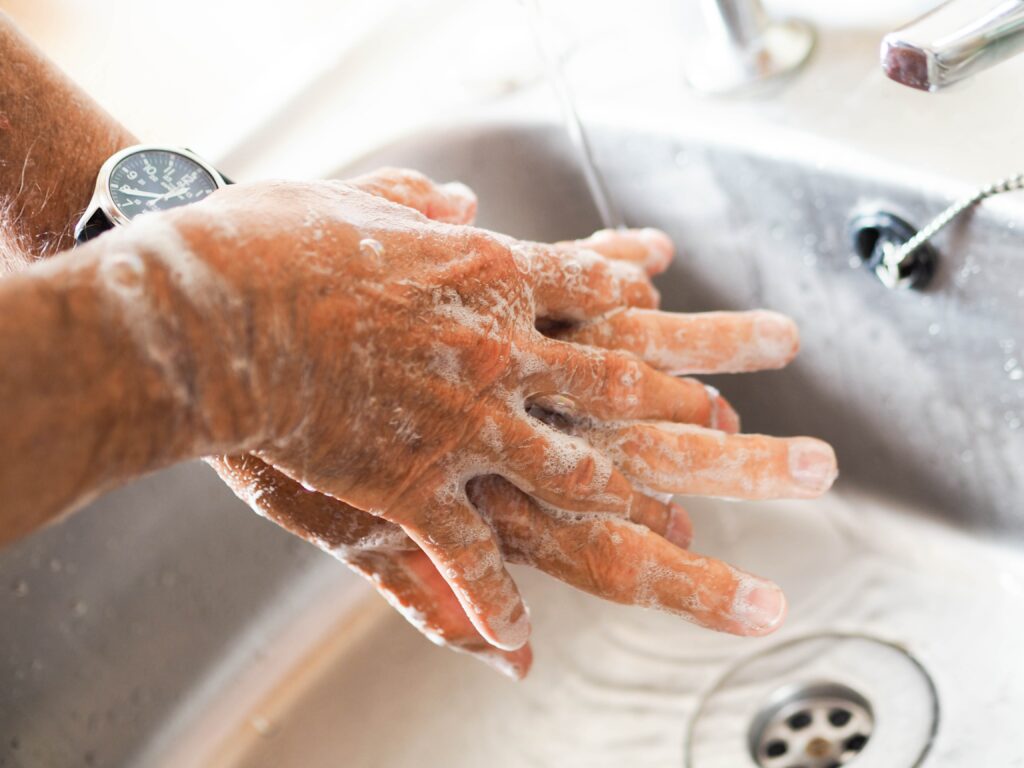 person washing hands underneath sink