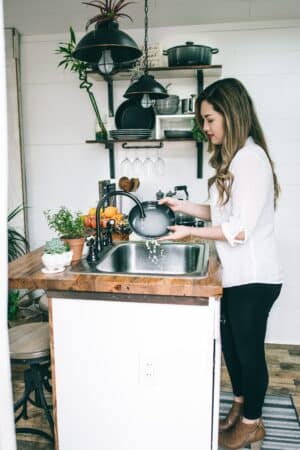 a woman wearing a white blouse washing dish on the faucet