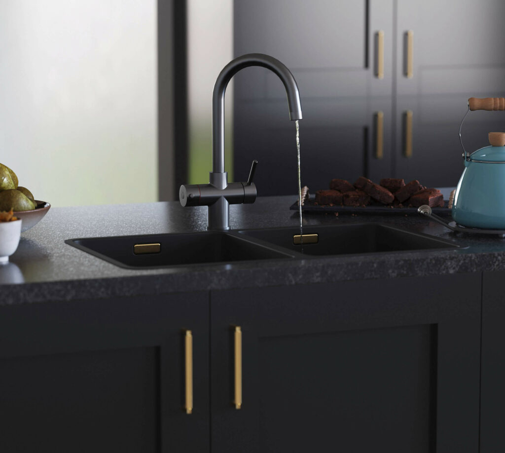 A gun metal boiling water tap running water in a modern kitchen with black cabinets