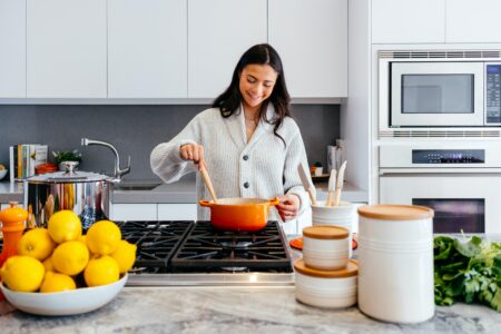 a woman cooking inside a modern white and grey kitchen