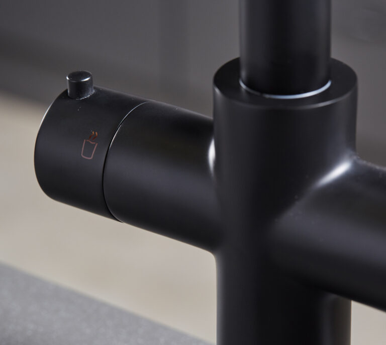 Close-up of a matte black hot water tap left handle